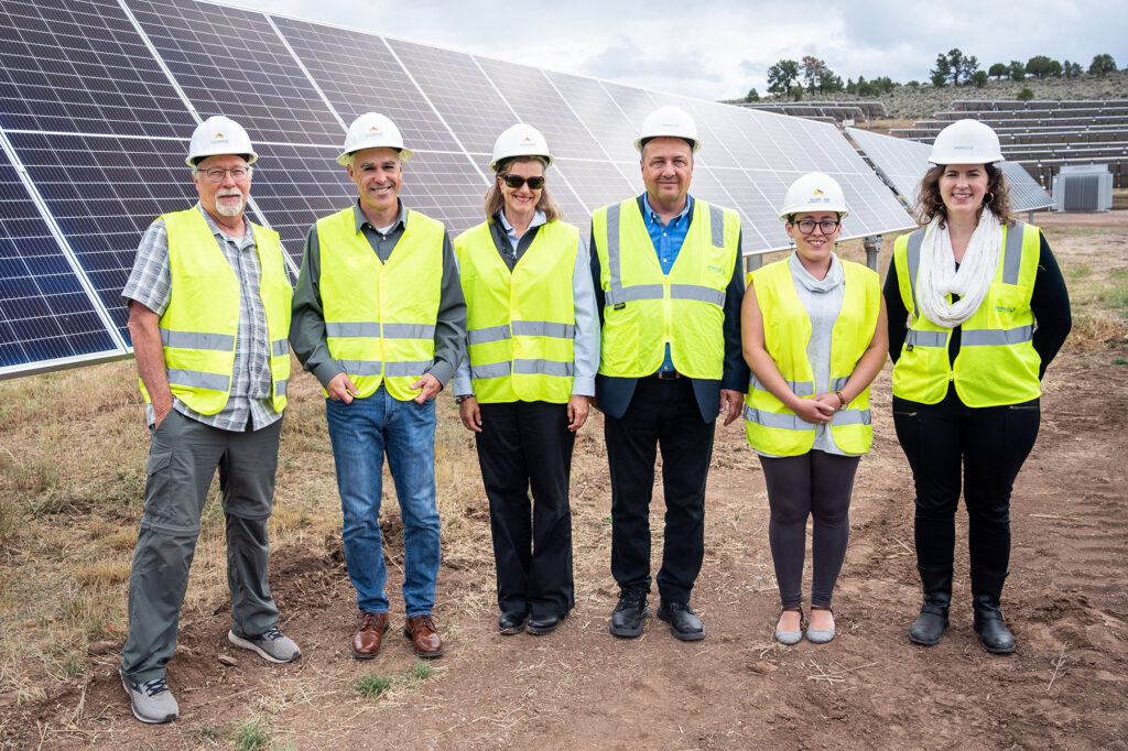 Leaders from CMC, Ameresco, and Holy Cross Energy in front of solar arrays at Spring Valley campus